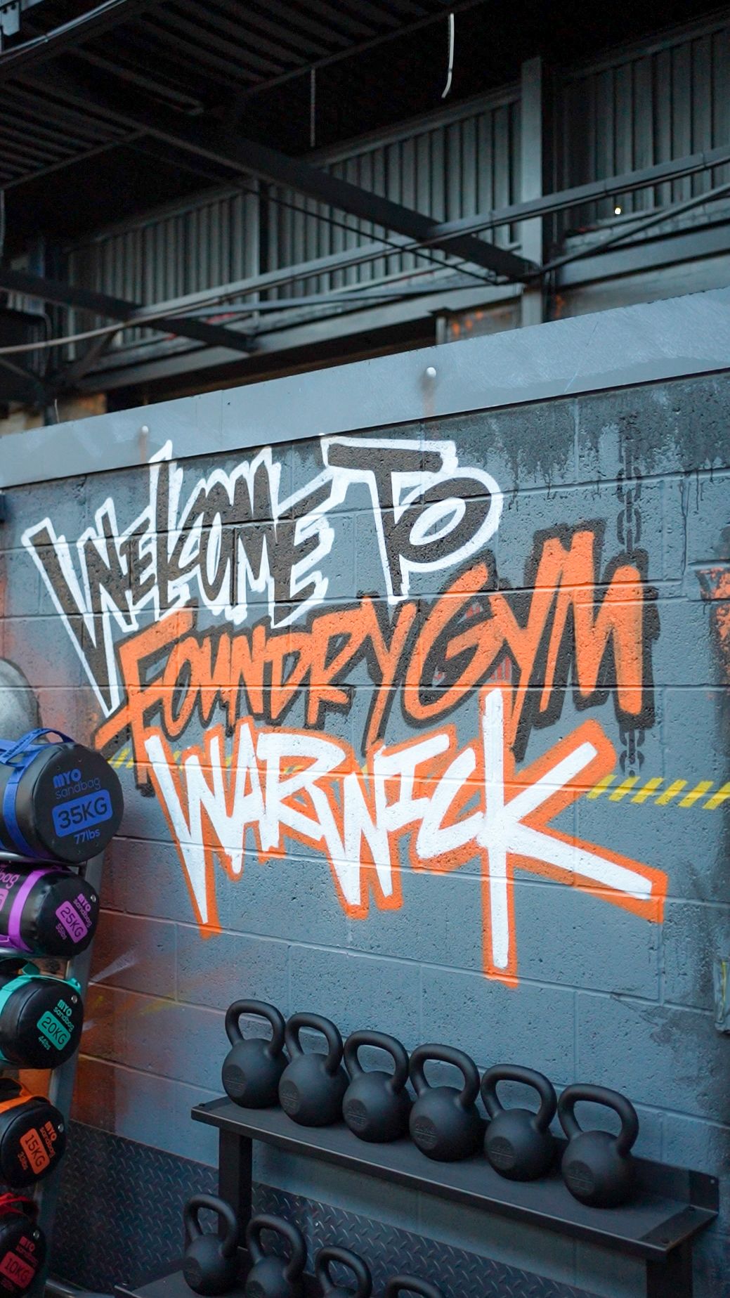 Welcome to Foundry Gym Warwick mural beside kettlebells